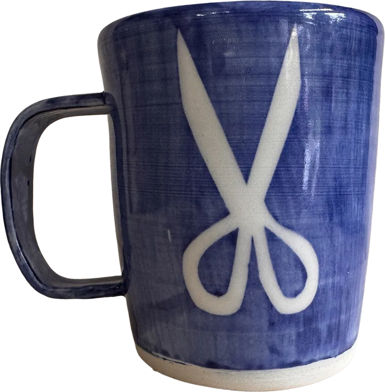 Cobalt blue mug with a pair of white silhouetted scissors.